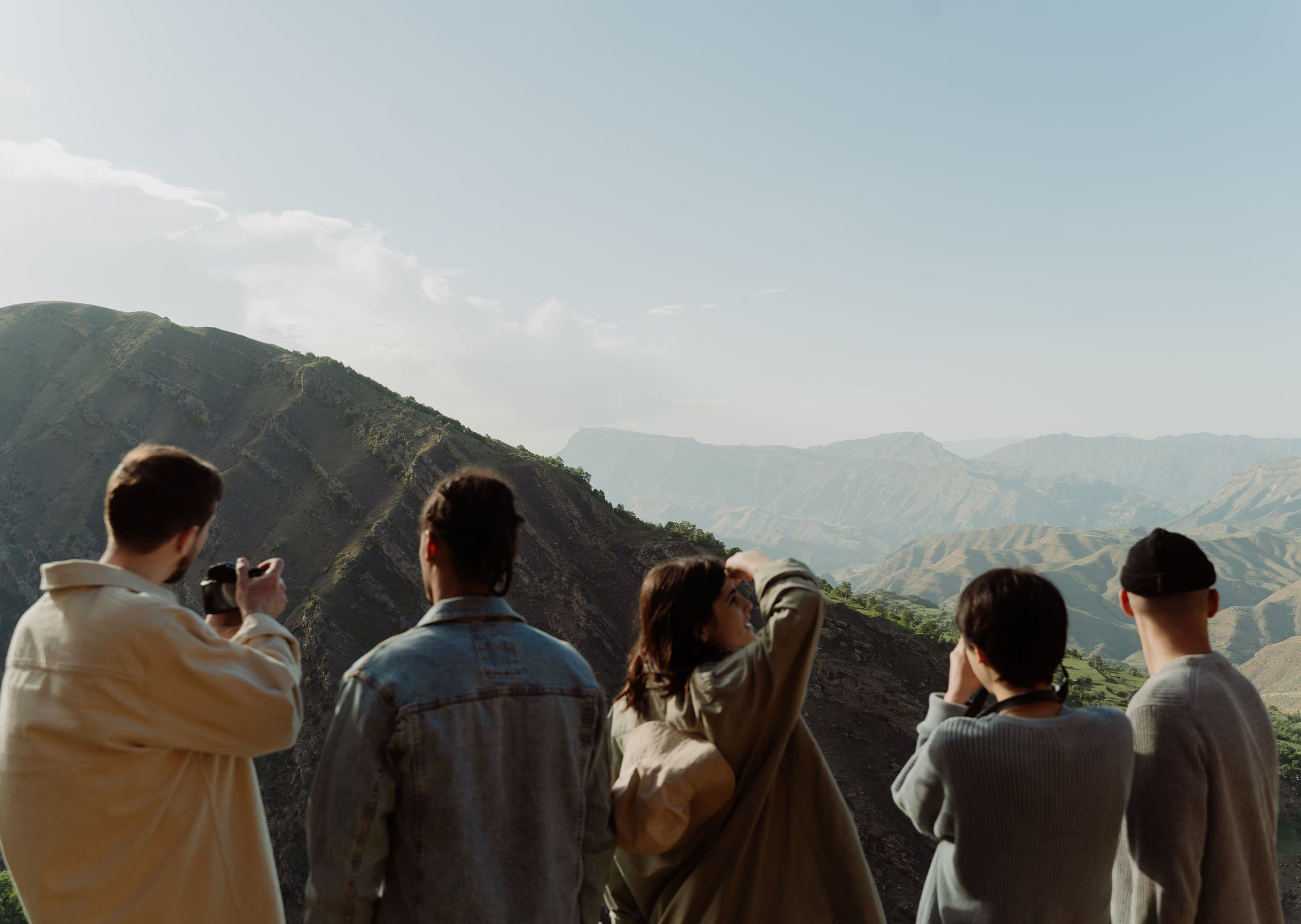 Five friends seen from behind, looking out over a mountain valley